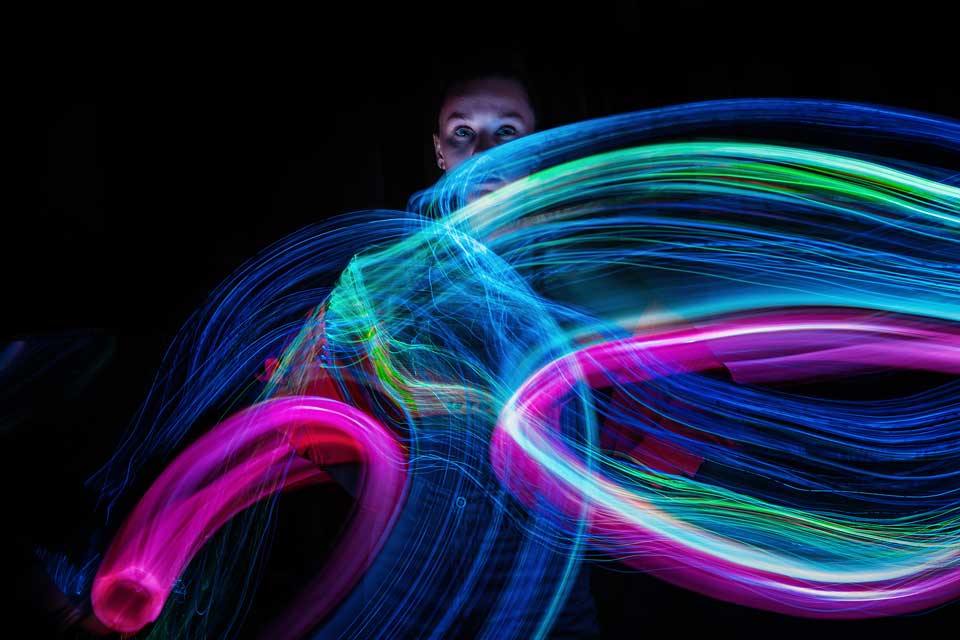 Traînées lumineuses néon colorées créées en light painting dans le noir
